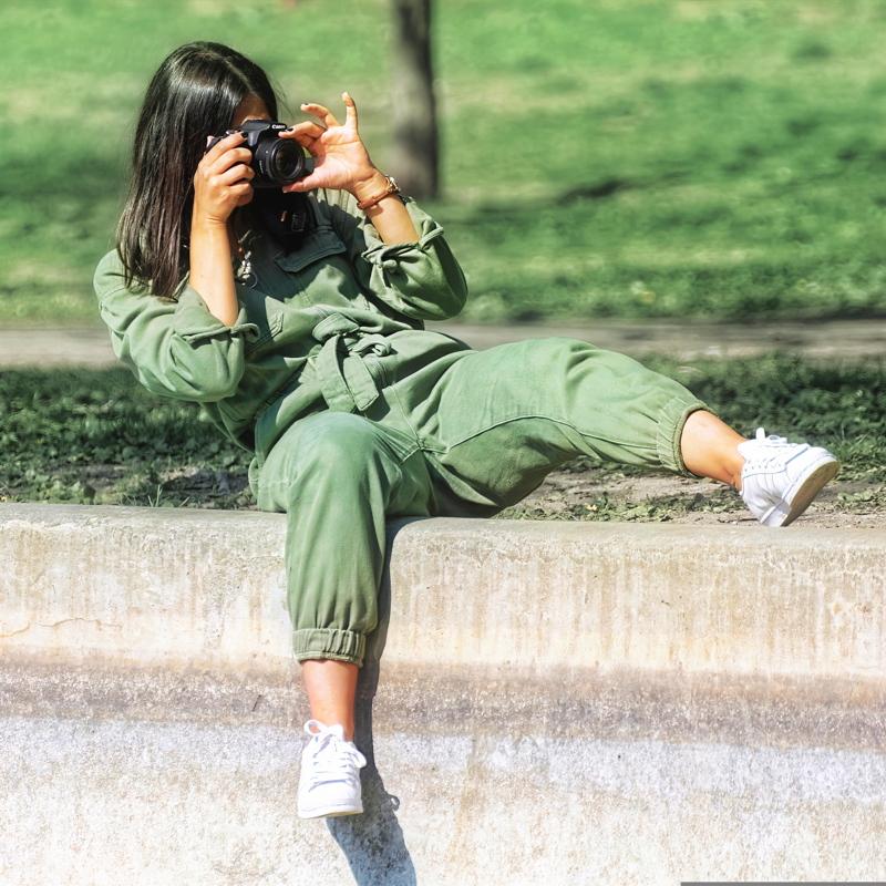 14 - A person photographing in a park while wearing a Sézane Hailey jumpsuit in khaki